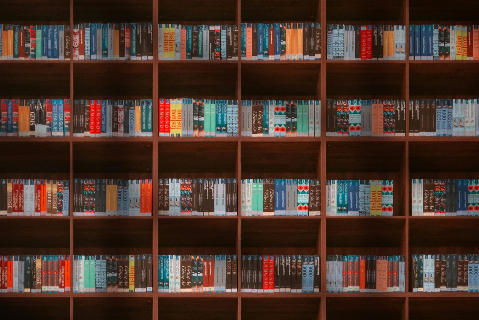 Koyu ahşap kütüphane raflarını dolduran renkli kitap sırtları